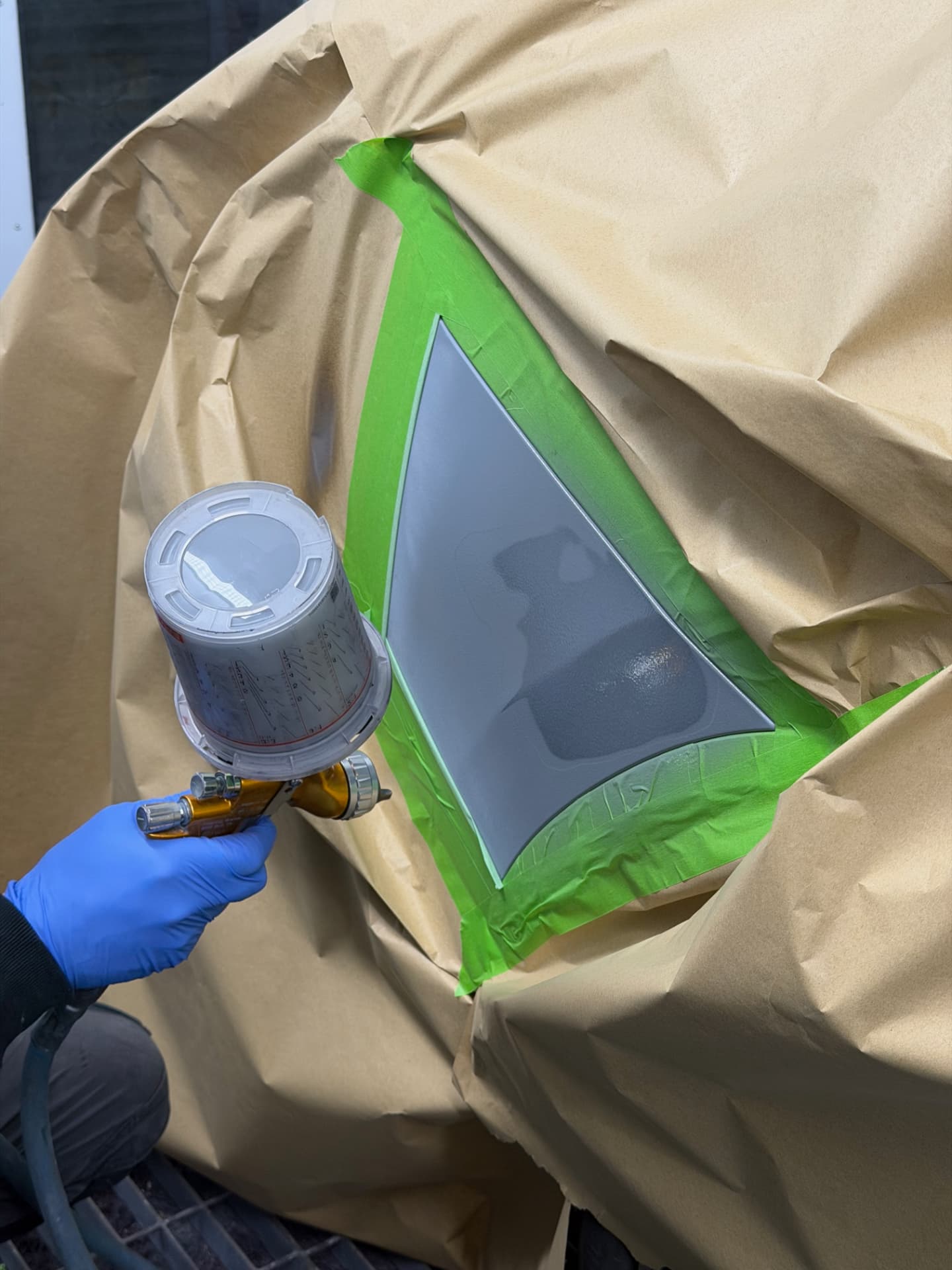 Masked panel being primed with a spray gun
