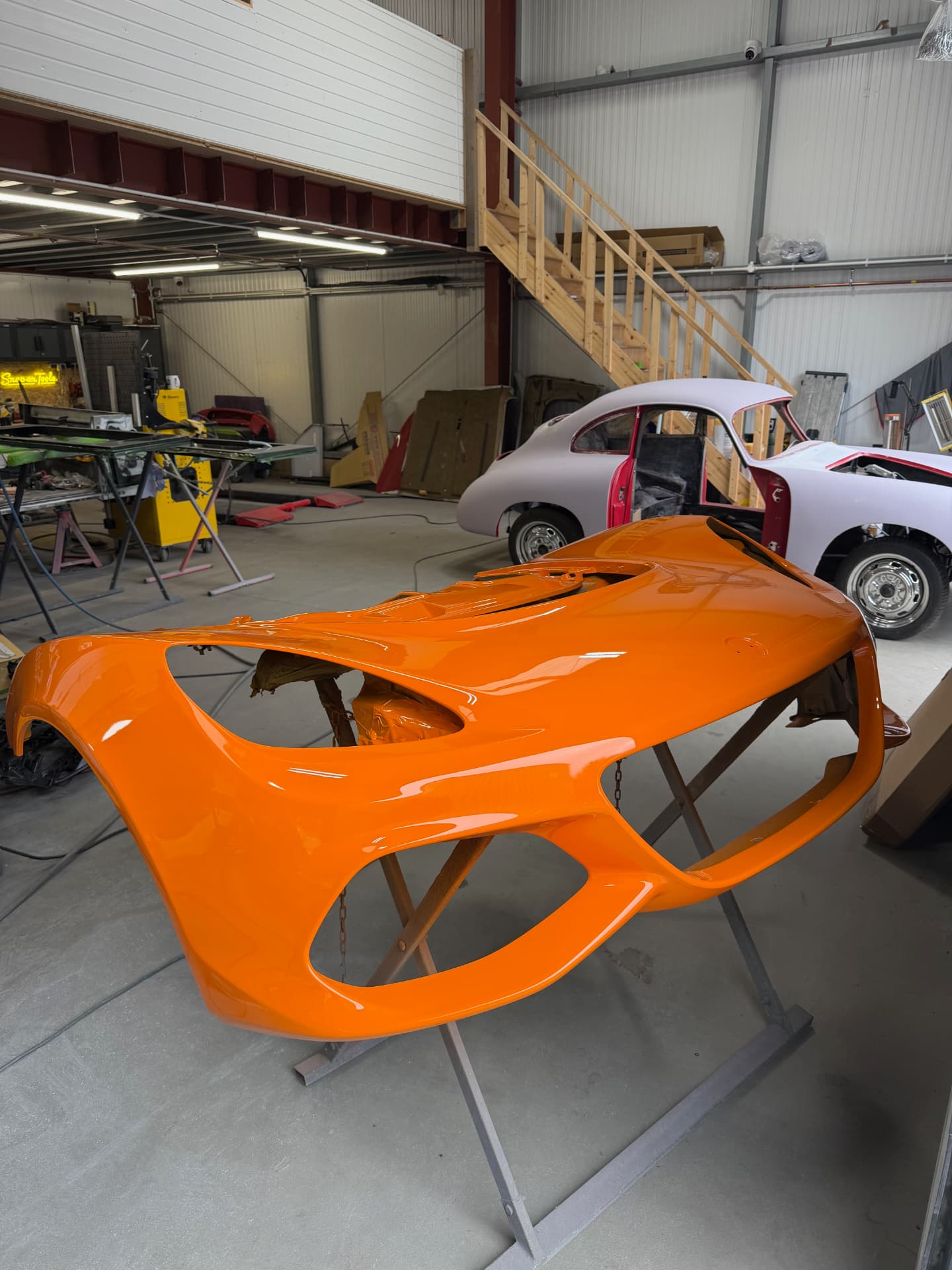 Freshly painted orange panel in the workshop with a classic Porsche behind