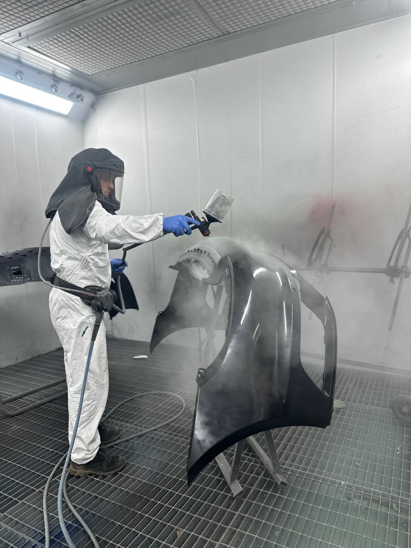 Spraying a black bumper in the paint booth