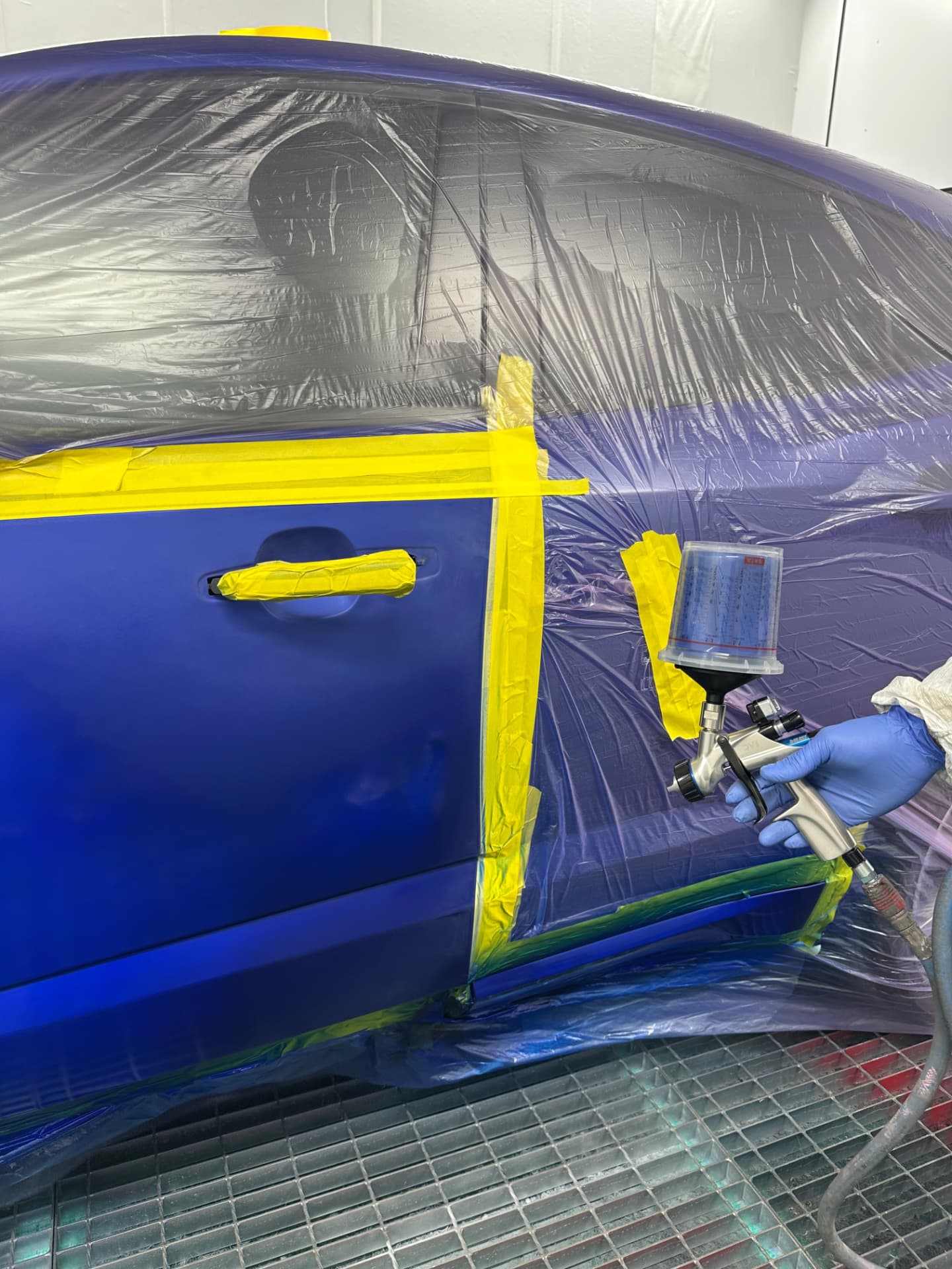 Close-up of fresh blue paint being applied to a car door