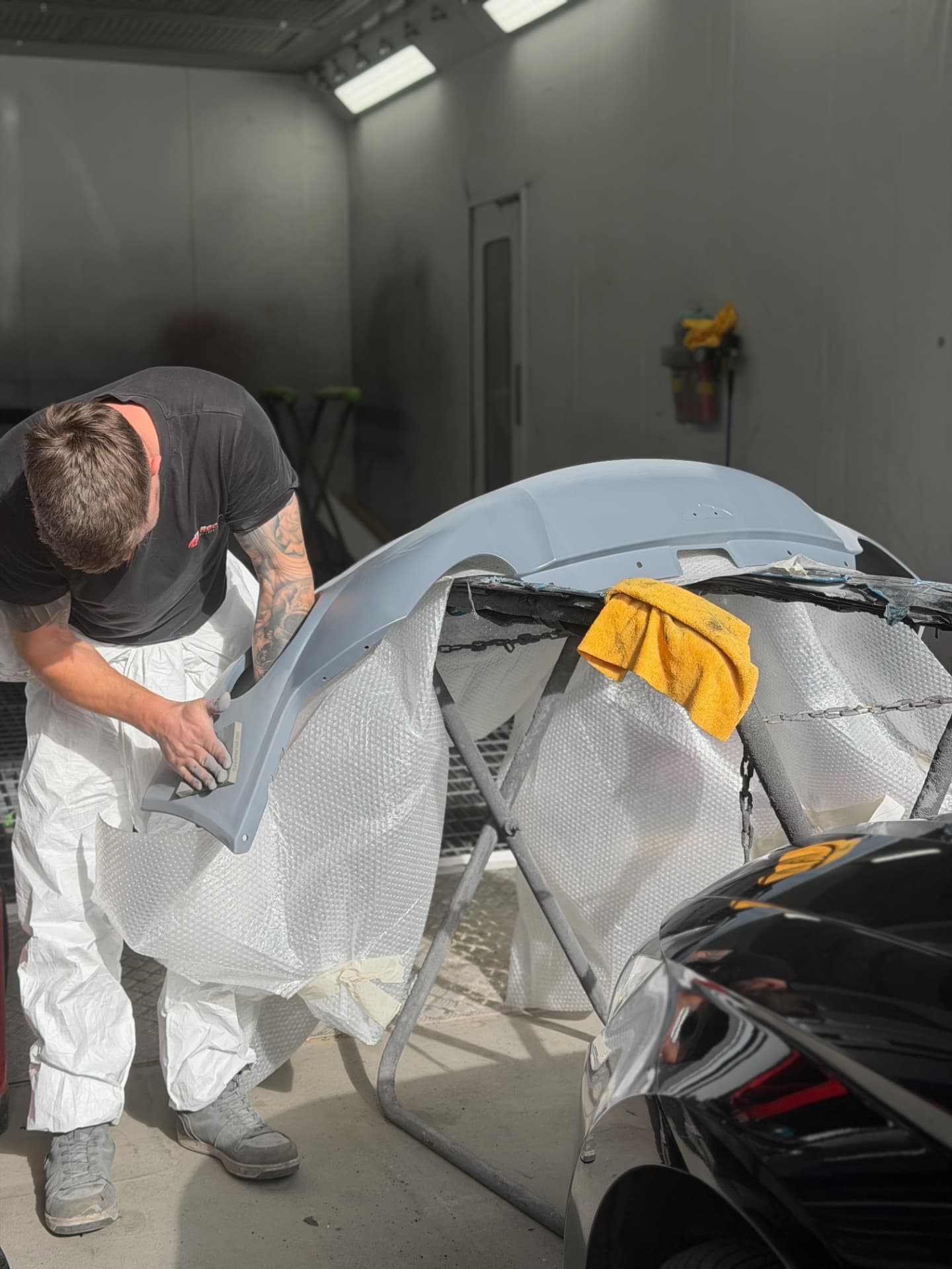 Technician fitting a freshly painted bumper to a car